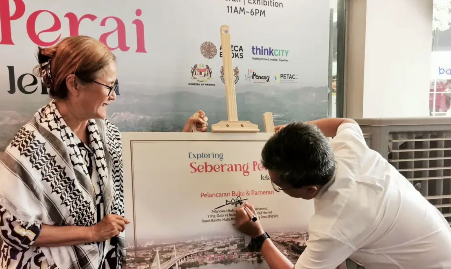 Seberang Perai Mayor Baderul Amin Abdul Hamid signing a poster a Khoo Salma Nasution's new book, 'Exploring Seberang Perai'